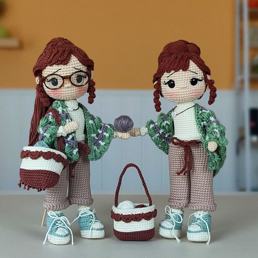 Muñeca amigurumi Nora Merino con chal verde y morado, bolso de crochet y zapatillas, sobre un fondo cálido.