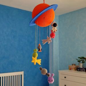 Móvil espacial de amigurumi tejido a crochet con un planeta naranja y azul, astronauta, extraterrestres, cohete, satélite y estrellas fugaces.